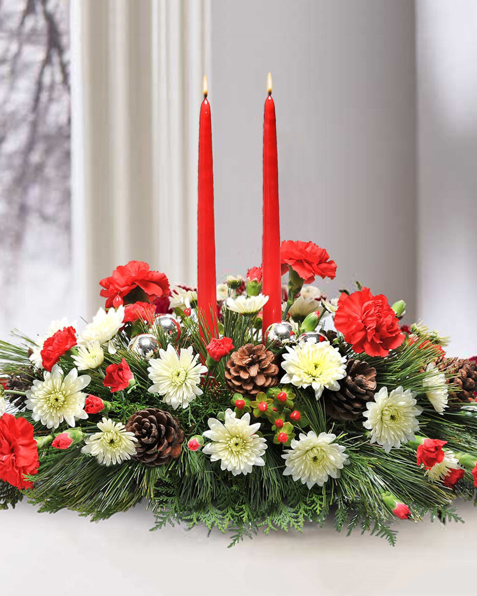 Christmas Cheer Centerpiece Standard Assorted Christmas Greens are complimented with Red Carnations, Red Mini Carnations, White Cushion Pom Pons, Red Hypericum, Pine Cones, Christmas Balls, and 2 Red Candles.
DELIVERY: Every order is hand-delivered direct to the recipient. These items will be delivered by us locally, or a qualified retail local florist.