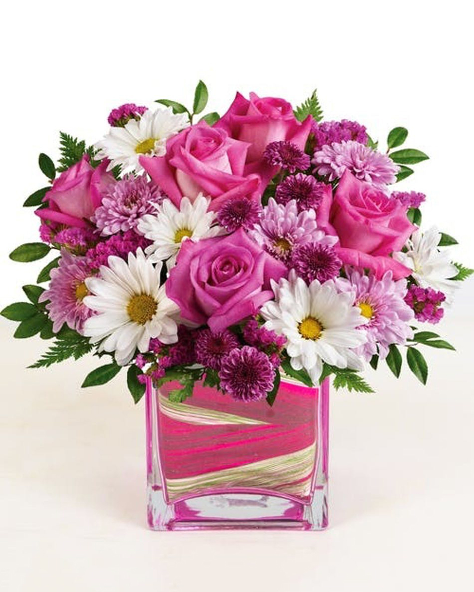 Fashionista Long Beach Deluxe-in a 6 x 6 Cube This beautiful design features stunning pink roses, purple mums, white daisies and more--it's perfect for any celebration!  Approximate sizes:  Standard 9