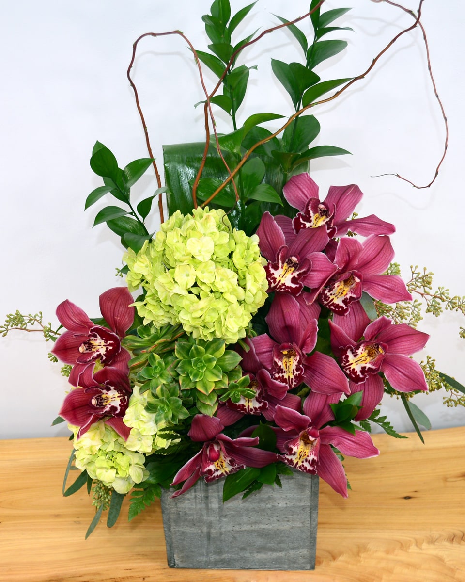 Islands Premium Islands-Luscious, exotic cymbidium orchids and tropical greens are elegantly arranged in a rustic wood box.
DELIVERY: Every order is hand-delivered direct to the recipient. These items will be delivered by us locally, or a qualified retail local florist.
