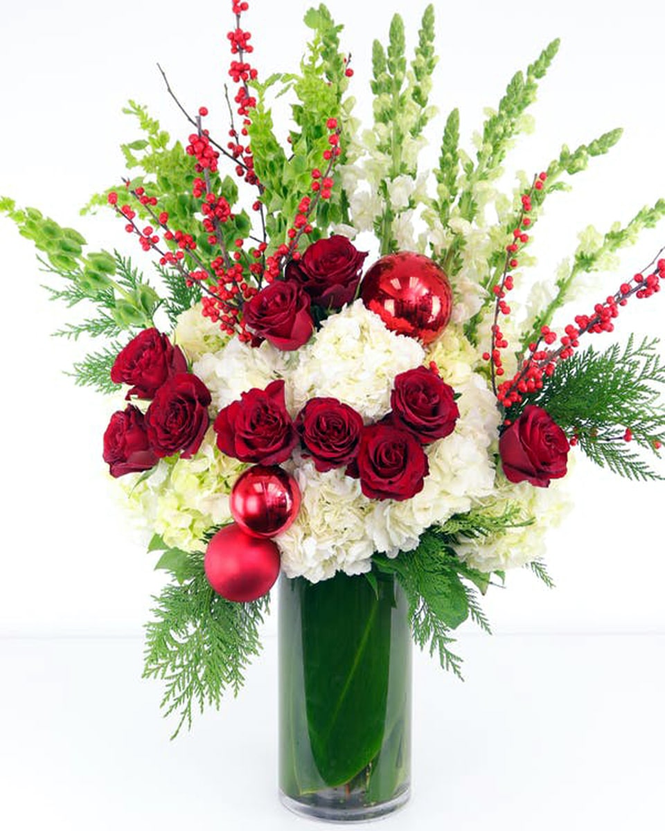 Deck the Halls Standard This showstopping holiday arrangement is sure to make a splash, featuring lush white hydrangea, long-stem red roses, white stock, belles of Ireland, REAL ilex berries and more!-