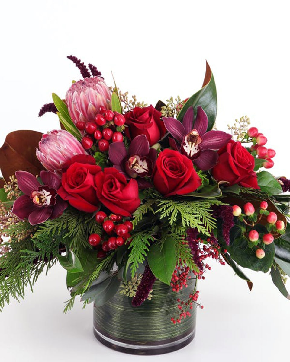 Winter Warmth Winter Warmth Winter Warmth-
This lush, low arrangement features the warm and rich colors of the season with red roses and winter textures made extra special by the addition of tropical orchid blooms and exotic protea.
Designed in a 6x6 glass cylinder.Arrangement measures about 10-11 inches tall.
DELIVERY: Every order is hand-delivered direct to the recipient. This item is only deliverable to local areas serviced by Allen’s Flower Market Stores. 
 