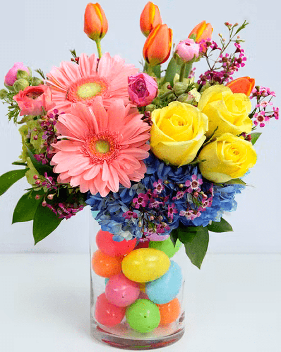 Easter Egg-Citement Standard A showcase of Spring sits atop playful plastic eggs in this arrangement that's sure to make them smile.