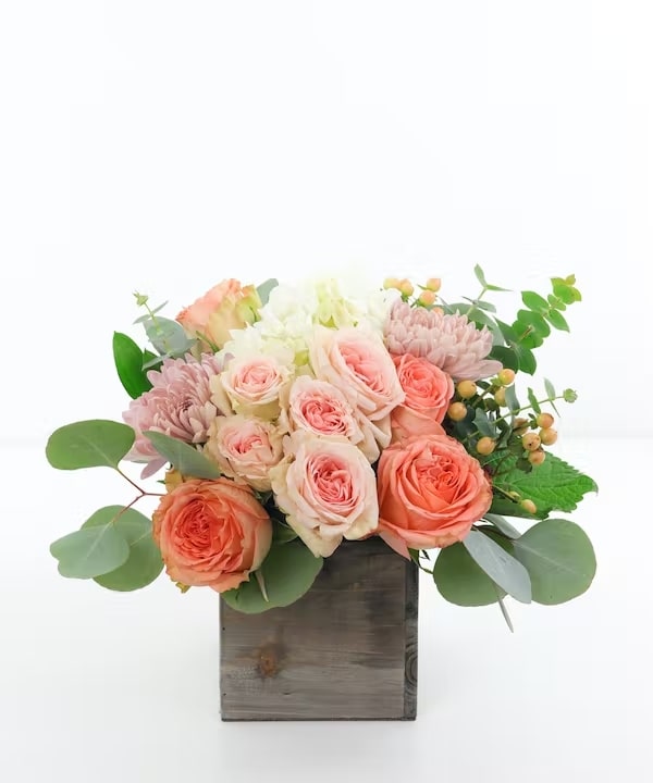 Feeling Peachy Standard Cast a little love with this peach, organic style arrangement. Ecuadorian garden roses, spray roses and South American hydrangea are arranged with locally grown organic accents in a wooden cube.
 
Every order is hand-delivered direct to the recipient. These items will be delivered by us locally, or a qualified retail local florist.