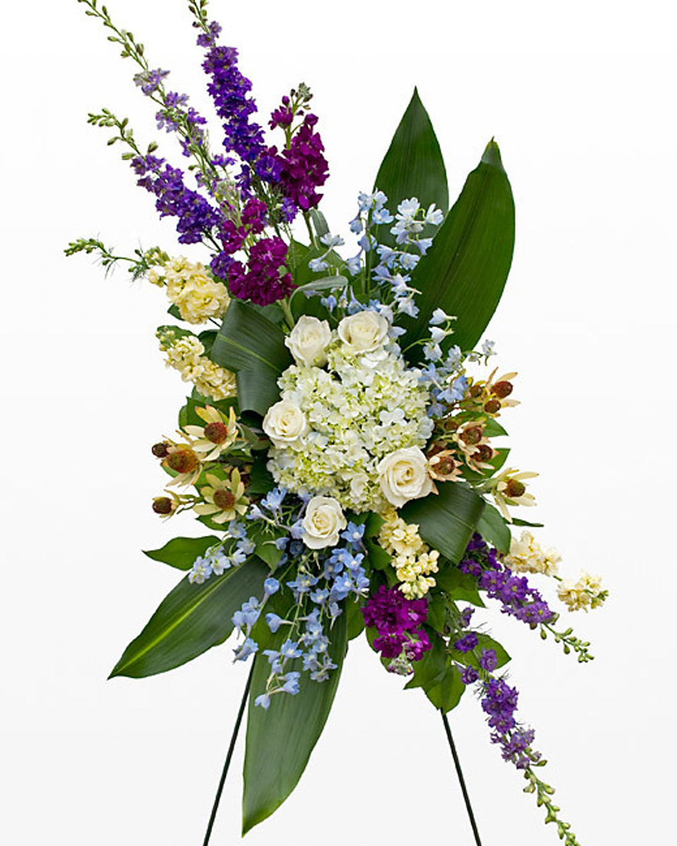 Pacific Standard A beautiful standing spray consisting of white hydrangea, roses, blue bella donna, purple larkspur, cream and purple stock, safari sunset, lemon and ti leaves. 
DELIVERY: Every order is hand-delivered direct to the recipient. These items will be delivered by us locally, or a qualified retail local florist.