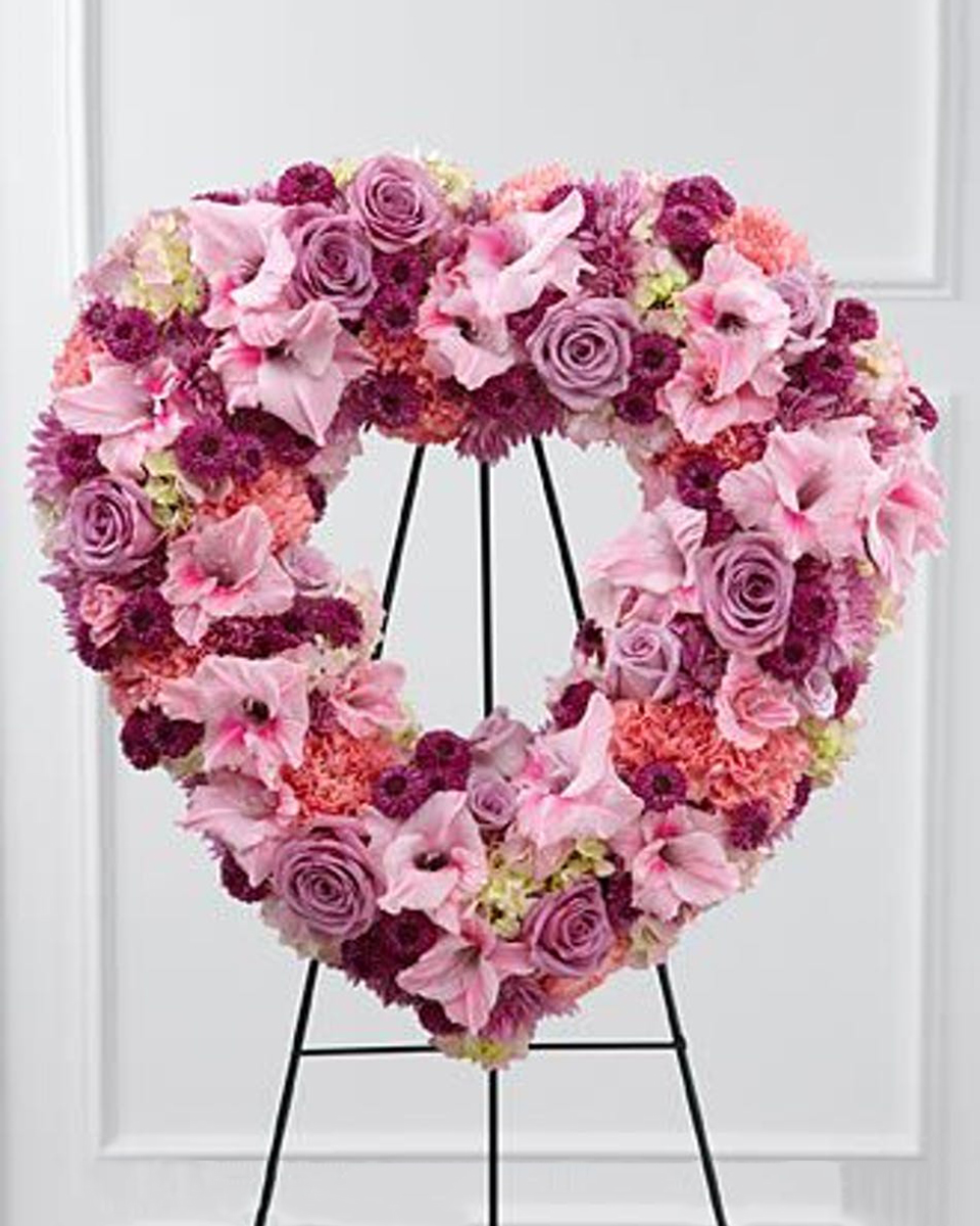 Hearts and Roses Standard (18 Inch) Purple Roses, Pink Gladiolus, Pink Carnations, Red and Lavender Pom Pons, and Hydrangea are arranged in an Open Heart Wreath.
DELIVERY: Every order is hand-delivered direct to the recipient. These items will be delivered by us locally, or a qualified retail local florist.
