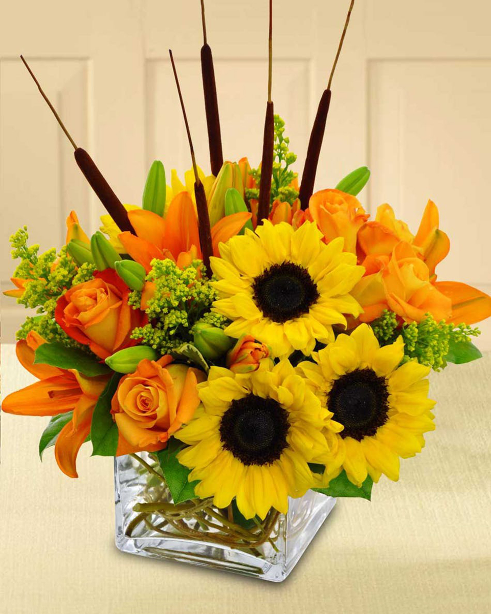 Autumn Breeze Standard Yellow sunflowers, orange tiger lilies, orange roses, cat tails, and solidago are crafted in a clear glass cube that is decoratively lined with curley willow.
DELIVERY: Every order is hand-delivered direct to the recipient. These items will be delivered by us locally, or a qualified retail local florist.