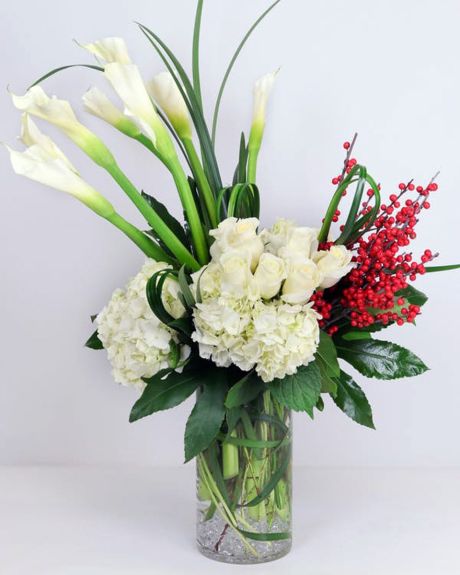 Winter white-Luscious white hydrangea, beautiful white calla lilies and premium ivory roses with seasonal berries are presented in a vase with clear gems.-Christmas Arrangement