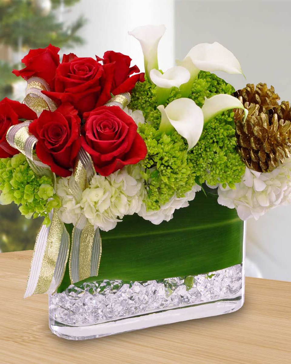 Jerusalem Jerusalem-Standard A real unique arrangement. An Oblong Glass Vase is first layered with Acrylic Rocks on its bottom. Ti Leaf then lines the vase above the Acrylic Rocks. White and Green Hydrangea are then compactly arranged with Red Roses, White Calla Lilies, and Gold Pine Cones designed above the Hydrangea.
DELIVERY: Every order is hand-delivered direct to the recipient. These items will be delivered by us locally, or a qualified retail local florist.